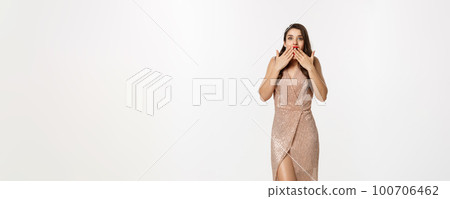 Party and celebration concept. Full-length of beautiful woman in elegant dress, standing near Christmas gifts and looking surprised, standing over white background Party and celebration concept. Full-length of beautiful woman in elegant dress, standing near Christmas gifts and looking surprised, standing over white background 100706462