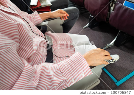 Passenger with fastened seat belt seated on aircraft seat for safety 100706847