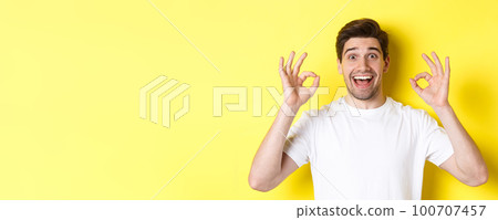 Amazed young man showing ok signs and smiling, recommending something good, standing over yellow background satisfied Amazed young man showing ok signs and smiling, recommending something good, standing over yellow background satisfied 100707457