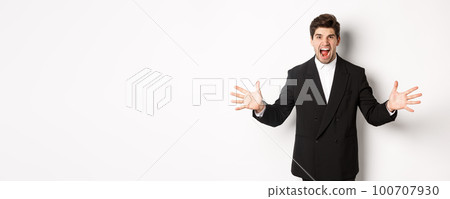Portrait of pissed-off and frustrated businessman in suit, shouting angry and shaking hands, standing distressed against white background 100707930