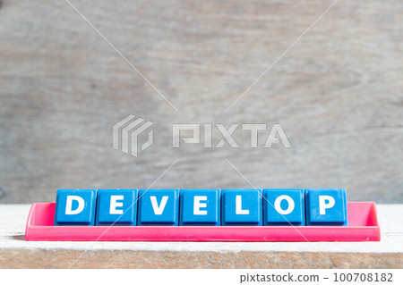 Tile alphabet letter with word develop in red color rack on wood background Tile alphabet letter with word develop in red color rack on wood background 100708182