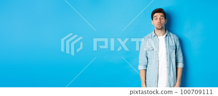 Handsome man waiting for kiss, pucker lips and close eyes while standing against blue background Handsome man waiting for kiss, pucker lips and close eyes while standing against blue background 100709111