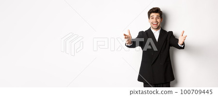 Portrait of happy attractive man in suit, hosting a party, reaching hands forward to greet you, want to hold something or hug, standing over white background Portrait of happy attractive man in suit, hosting a party, reaching hands forward to greet you, want to hold something or hug, standing over white background 100709445