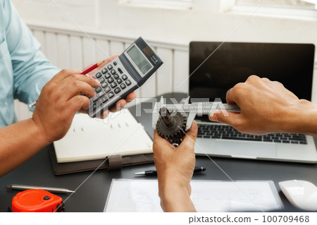 The engineering team is working on their project together. Man work with caliper measure the motor gear, engine part. The engineering team is working on their project together. Man work with caliper measure the motor gear, engine part. 100709468