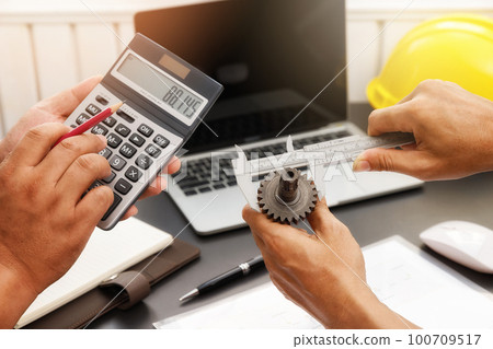 The engineering team is working on their project together. Man work with caliper measure the motor gear, engine part. The engineering team is working on their project together. Man work with caliper measure the motor gear, engine part. 100709517