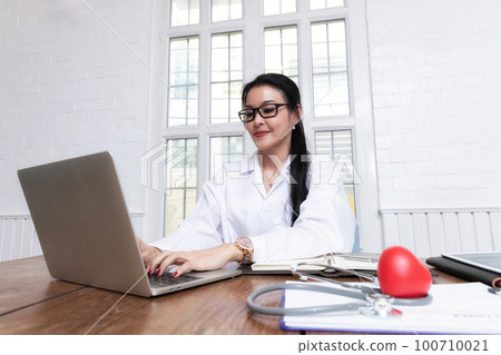 Female doctor working with laptop at office desk in the hospital. Concept of health care and medical. 100710021