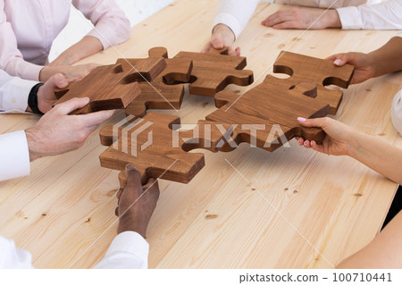 Hands assembling jigsaw puzzle Hands assembling jigsaw puzzle 100710441