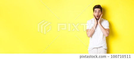 Image of handsome man looking surprised, gasping and saying wow, looking at promo offer amazed, standing over yellow background Image of handsome man looking surprised, gasping and saying wow, looking at promo offer amazed, standing over yellow background 100710511