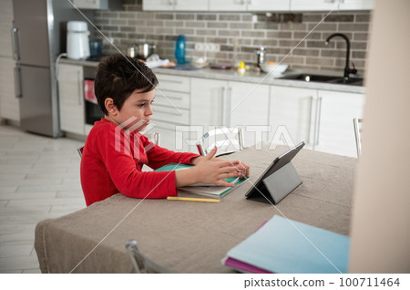 Smart teenage boy, school child doing homework with digital tablet at home. Kid using gadgets to study. Education and distance learning for kids. Homeschooling during quarantine. Online courses Smart teenage boy, school child doing homework with digital tablet at home. Kid using gadgets to study. Education and distance learning for kids. Homeschooling during quarantine. Online courses 100711464