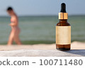 Bottle with dropper and clear label on wooden trunk, mock-up for cosmetic product. Tanning oil 100711480
