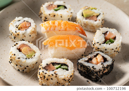 Closeup homemade sushi rolls with salmon, shrimp, avocado i n a round plate 100712196