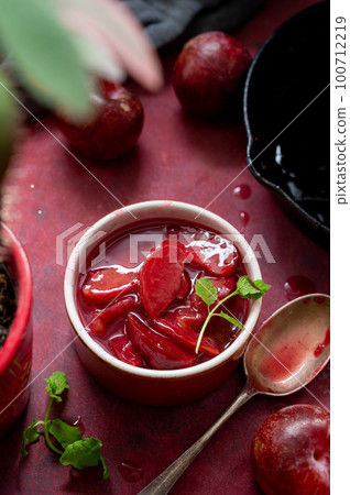 Red plums confiture, jam or fruit sauce in a bowl, top voiew Red plums confiture, jam or fruit sauce in a bowl, top voiew 100712219