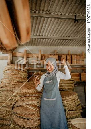 muslim female entrepreneur raise arm in her workshop 100714228
