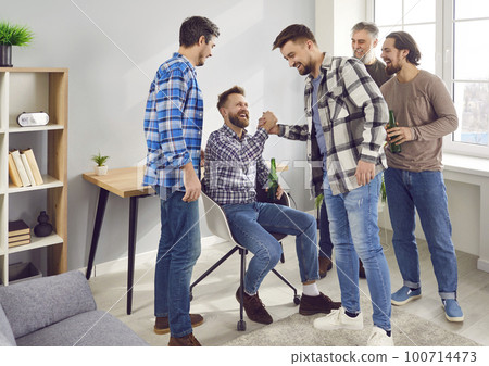 Happy male friends greet each other and shake hands as they meet at a party at home 100714473