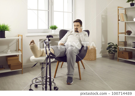 Young man is lying on the couch at home with broken leg in gypsum. Young man is lying on the couch at home with broken leg in gypsum. 100714489