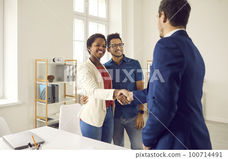 Happy black couple meeting and shaking hands with realtor, loan broker or insurance advisor Happy black couple meeting and shaking hands with realtor, loan broker or insurance advisor 100714491
