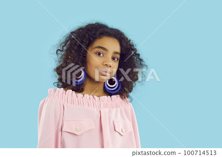 Portrait of cute pretty dark-skinned curly preteen girl isolated on light blue background. Portrait of cute pretty dark-skinned curly preteen girl isolated on light blue background. 100714513