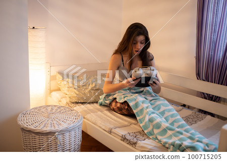 The surprised girl holds a large alarm clock in her hands. 100715205