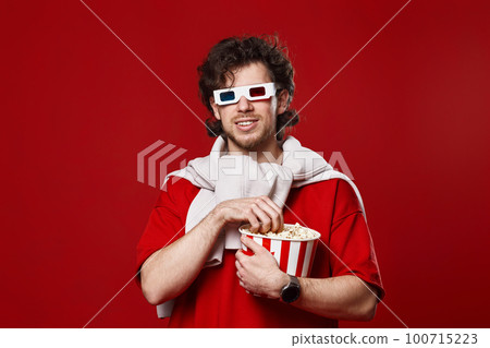 man in 3d glasses holding big bucket of popcorns 100715223