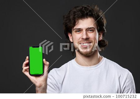 happy young man showing phone with green screen 100715232