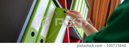 Secretary takes out business folder with documents from cabinet Secretary takes out business folder with documents from cabinet 100715648