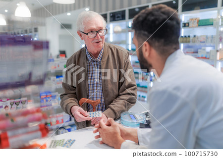 Young pharmacist explaining to customer how to dosing medication. 100715730