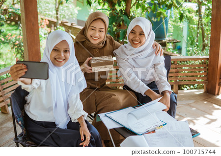 two students and the teacher in veil selfie together 100715744