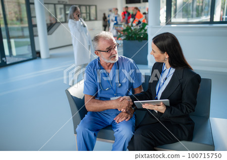 Young business woman shaking hand with elderly doctor. Young business woman shaking hand with elderly doctor. 100715750
