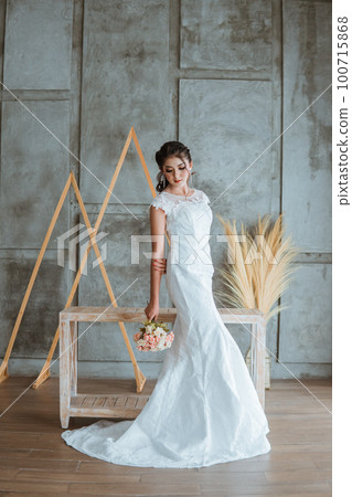 beautiful asian bride in white gown standing and looking down 100715868