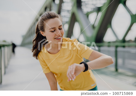 Young woman checking smartwatch in city, preparing for run, healthy lifestyle and sport concept. Young woman checking smartwatch in city, preparing for run, healthy lifestyle and sport concept. 100715869