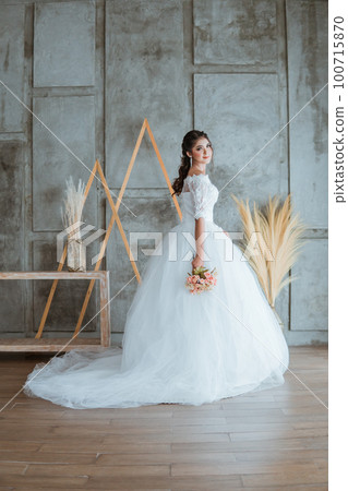 bride in white gown standing with the flowers bouquet at her hand bride in white gown standing with the flowers bouquet at her hand 100715870