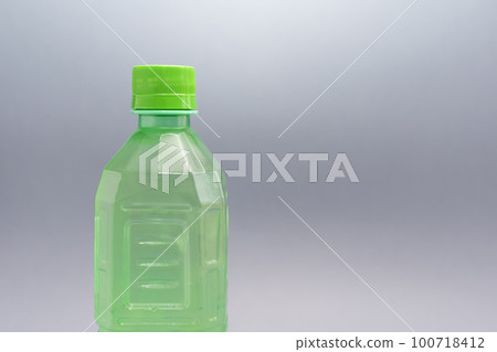 Closeup Green Ribbed Plastic Bottle With Liquid, Juice On Grey Background. Copy space for text, horizontal plane Closeup Green Ribbed Plastic Bottle With Liquid, Juice On Grey Background. Copy space for text, horizontal plane 100718412