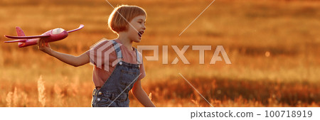 Child launches a toy plane in the field Child launches a toy plane in the field 100718919