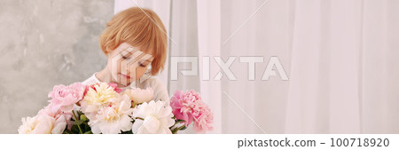 Girl 6-7 years old in a white dress holds a flower Girl 6-7 years old in a white dress holds a flower 100718920
