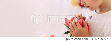 Girl 6-7 years old in a white dress holds a flower Girl 6-7 years old in a white dress holds a flower 100718924