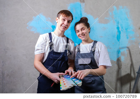 House decoration DIY renovation concept. Happy couple in empty room of new home planning design. Husband and wife holding swatch palette choosing colors for painting wall in new house House decoration DIY renovation concept. Happy couple in empty room of new home planning design. Husband and wife holding swatch palette choosing colors for painting wall in new house 100720789