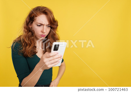 Worried redheaded woman using a mobile phone Worried redheaded woman using a mobile phone 100721463