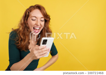 Redheaded woman laughing while using the mobile phone Redheaded woman laughing while using the mobile phone 100721468