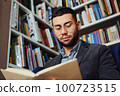 Intelligent man reading book in book shop 100723515