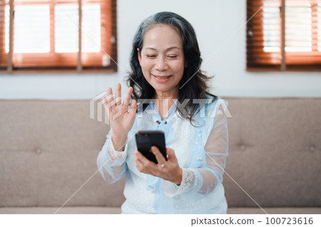 Portrait of an elderly Asian woman holding a mobile phone with eating snacks and drinking tea Portrait of an elderly Asian woman holding a mobile phone with eating snacks and drinking tea 100723616