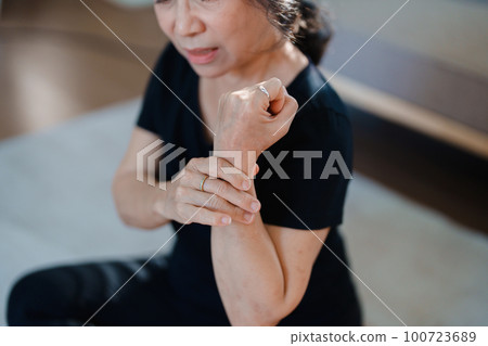 Portrait of an elderly Asian woman showing wrist pain during exercise. 100723689