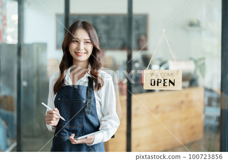 open a small business Portrait of happy Asian woman in apron holding tablet in front of cafe open a small business Portrait of happy Asian woman in apron holding tablet in front of cafe 100723856