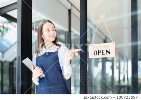 Starting and opening a small business, a young Asian woman showing a smiling face in an apron standing in front of a coffee shop bar counter. Business Owner, Restaurant, Barista, Cafe, Online SME. 100723857