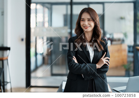 Portrait of a woman business owner showing a happy smiling face as he has successfully invested her business using computers and financial budget documents at work. Portrait of a woman business owner showing a happy smiling face as he has successfully invested her business using computers and financial budget documents at work. 100723858