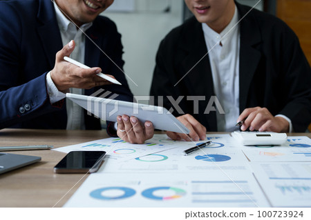 Concept of the impact of warring countries, male economists are using tablets to consult with marketing staff or accountants to adjust production and investment strategies to the current situation. 100723924