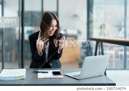 Portrait of a woman business owner showing a happy smiling face as he has successfully invested her business using computers and financial budget documents at work. Portrait of a woman business owner showing a happy smiling face as he has successfully invested her business using computers and financial budget documents at work. 100724074