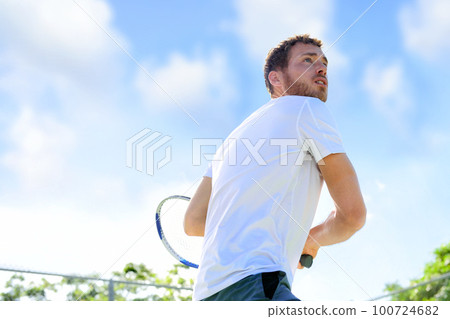 Tennis player man playing game hitting ball finishing serve outdoor. Sport fitness athlete outside with tennis racket. Fit young male caucasian professional living healthy active lifestyle. Tennis player man playing game hitting ball finishing serve outdoor. Sport fitness athlete outside with tennis racket. Fit young male caucasian professional living healthy active lifestyle. 100724682