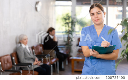 Smiling young female doctor filling out medical form Smiling young female doctor filling out medical form 100725400