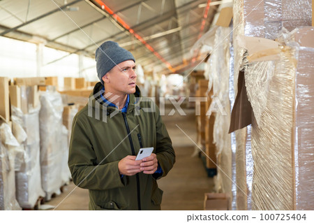 Store warehouse employee scans barcode on boxes using phone 100725404