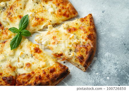 Italian pizza four cheeses with stretching cheese and basil on a light concrete background Italian pizza four cheeses with stretching cheese and basil on a light concrete background 100726850